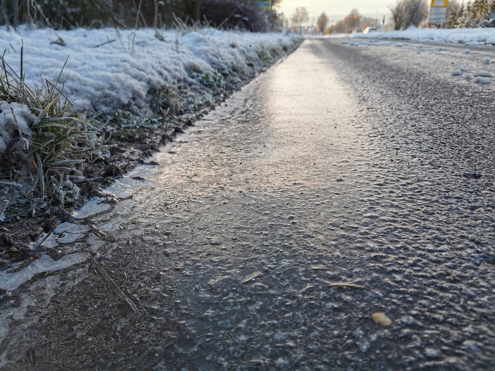 Ice covering a pedestrian walkway beside banks of snow